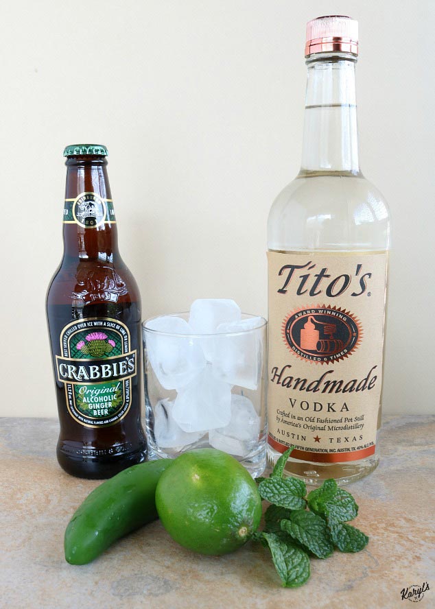 shot of Austin Mule ingredients: bottles of vodka and ginger beer, glass with ice, mint, lime and jalapeno garnish in front 