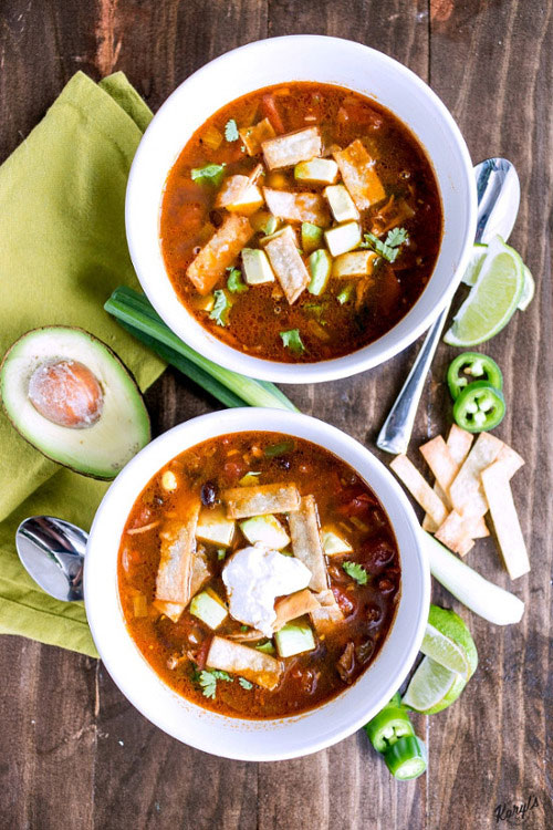 Chicken Tortilla Soup will warm you up with tender chicken, lots of veggies, and a bold kick from the spices. Finish with homemade tortilla strips, diced avocado, a little sour cream and sharp cheese. Ready in under 30 minutes on the stove, or in the crock pot after a long day #chicken #corn #blackbeans #jalapeno #tortillastrips #chickentortillasoup #spicysoup #easyrecipe #comfortfood #karylskulinarykrusade