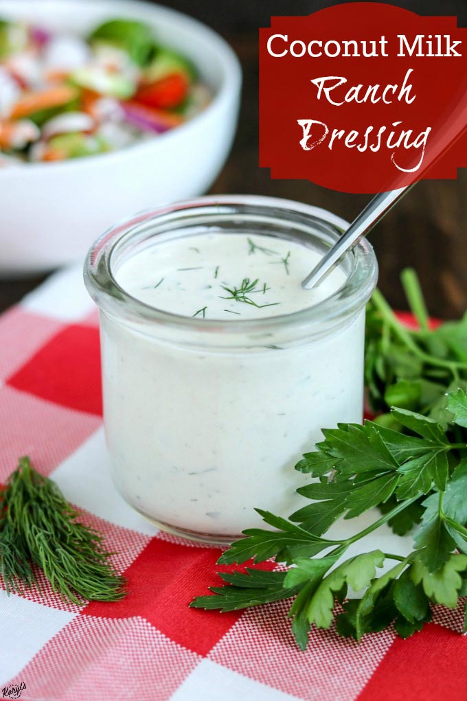 front shot of Coconut Milk Ranch Dressing in a glass jar with a spoon on a plaid napkin with salad in teh background