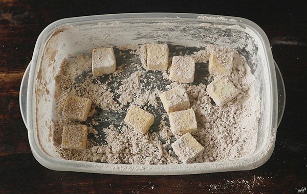 overhead shot of tofu pieces in container with cornstarch mixture