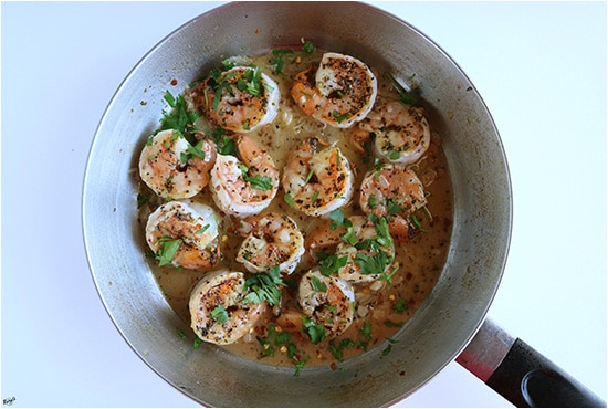 Process shot: shrimp in skillet with sauce, and garnished with parsley