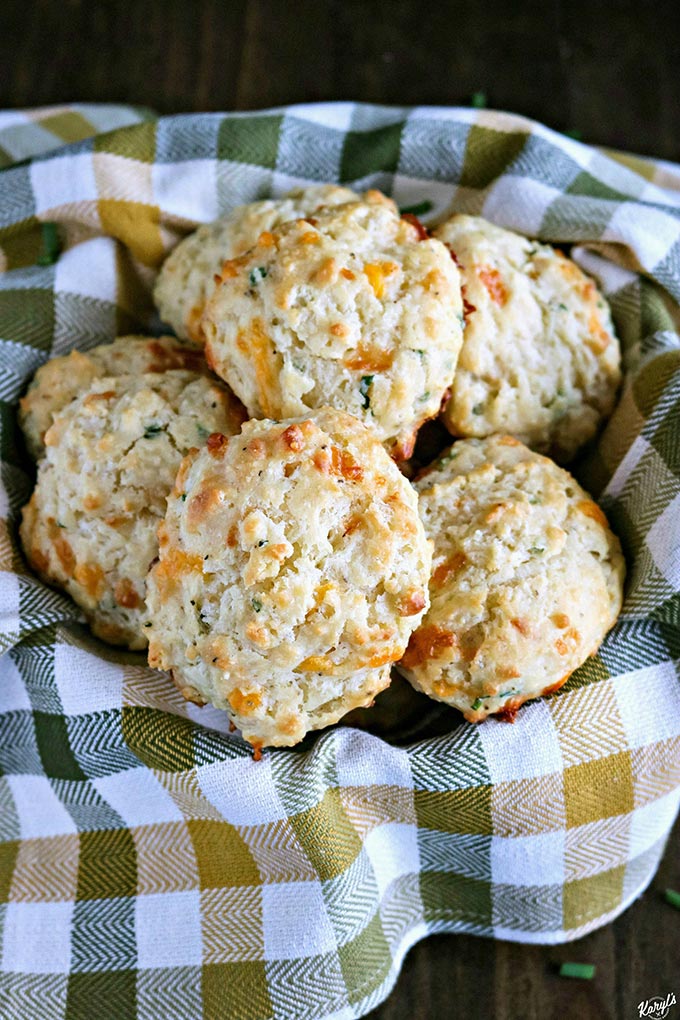overhead shot of Cheddar Chive Drop Biscuits in a basket with a green and tan napkin