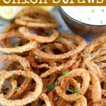 close up angled shot of finished onion straws with a side of dipping sauce