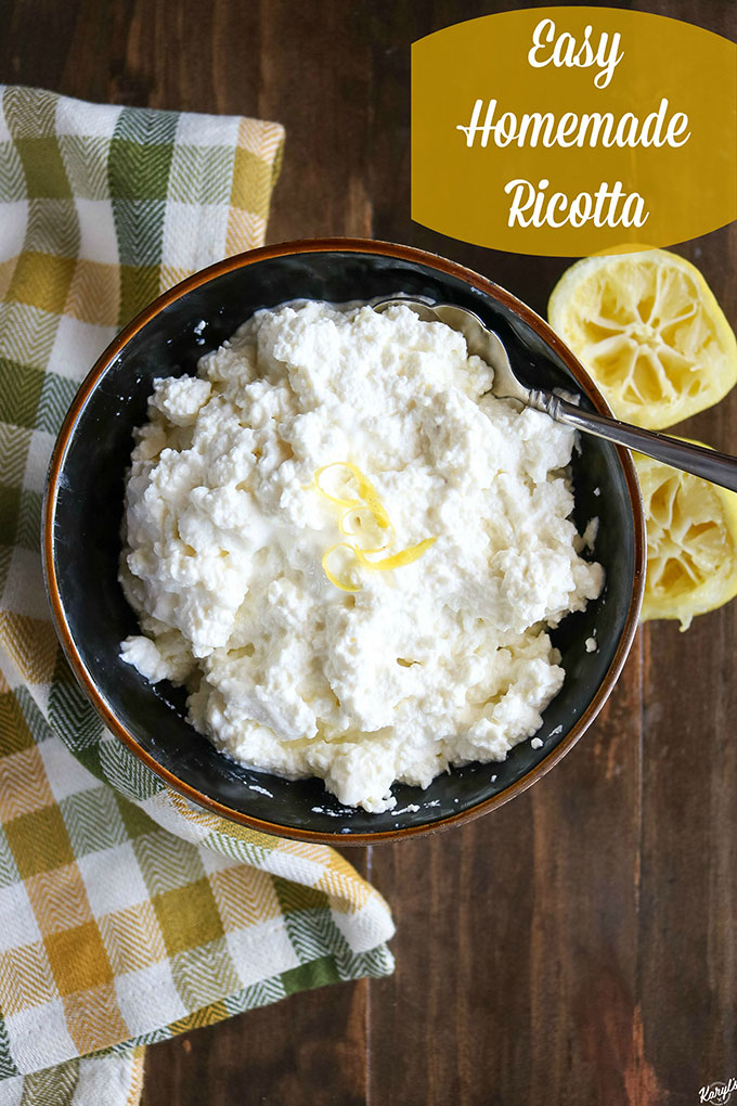 overhead shot of finished ricotta in a black bowl, with lemon wedges on right side