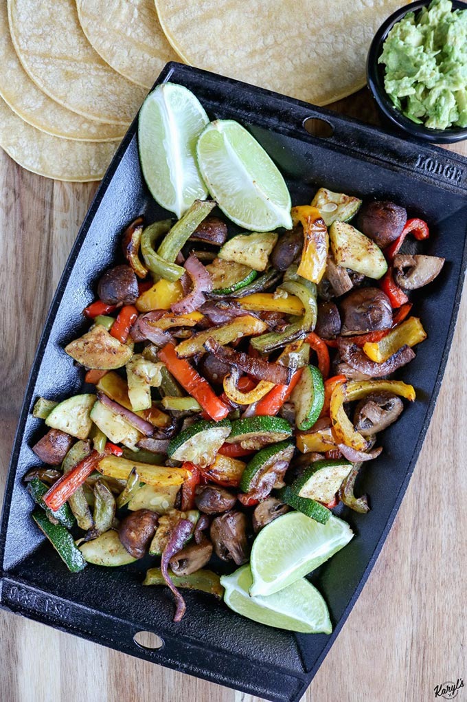 overhead shot of finished veggie fajitas in a skillet with lime wedges on the side