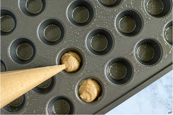 overhead process shot: piping batter into mini muffin pan