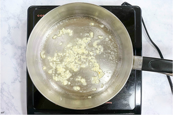 overhead process shot: butter and minced garlic in a stainless steel skillet