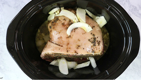overhead process shot: pork, onion, garlic, and orange juice in a crock pot