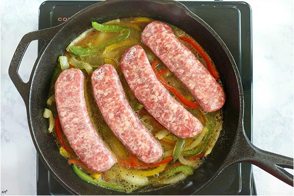 overhead process shot: brats, veggies and beer cooking in a skillet