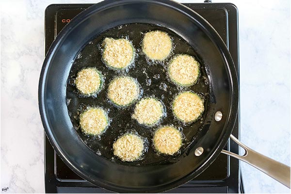 overhead process shot: zucchini frying in a black skillet