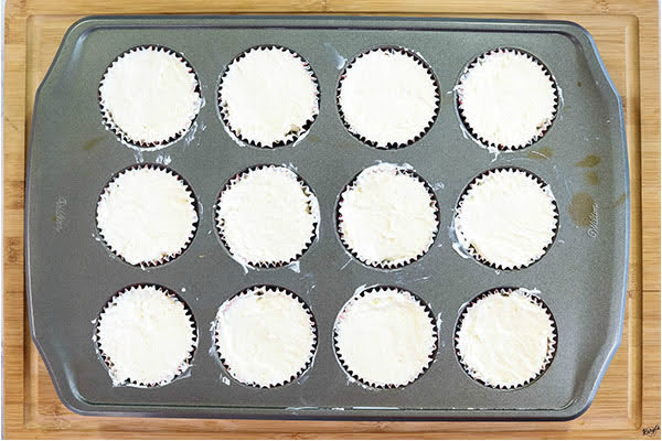 overhead process shot: cheesecake topping added to muffin liners, ready to chill