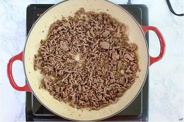 Overhead process shot: ground beef cooking in a braiser