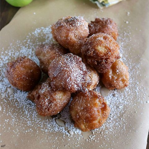 Angled shot of a stack of finished Bourbon Apple Fritters on brown paper