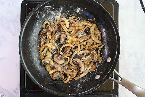 Overhead process shot: onions, mushrooms and flour in a black skillet 